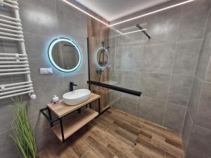 ein Badezimmer mit Waschbecken und Dusche mit Spiegel in der Unterkunft Apartament Bałtycka & Bike Room in Kołobrzeg + 19 Fotos