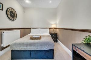 Un dormitorio con una cama con un reloj en la pared. en 4BR Cottage, Parking, NEC, Birmingham Airport, en Birmingham