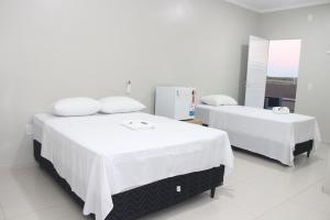 two beds in a room with white walls at Liziane Souza da Silva in Catarina