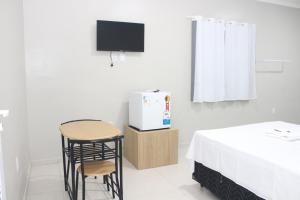a room with a bed and a table and a tv at Liziane Souza da Silva in Catarina