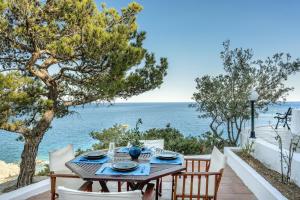 a table and chairs on a patio with a view of the ocean at SeaScape Boutique Villa in Achlia