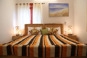 a bedroom with a bed with a striped comforter and two lamps at Villa Baywalk Goa - 200 meters from Morjim Beach in Morjim