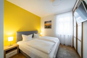 ein Schlafzimmer mit einem weißen Bett und einer gelben Wand in der Unterkunft Ferienwohnung "Düne" im Ostsee-Domizil Sandburg in Kühlungsborn