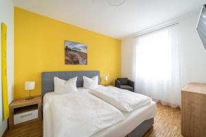 ein Schlafzimmer mit einem weißen Bett und einer gelben Wand in der Unterkunft Ferienwohnung "Düne" im Ostsee-Domizil Sandburg in Kühlungsborn