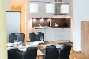 einen Esstisch mit schwarzen Stühlen und eine Küche in der Unterkunft Ferienwohnung "Düne" im Ostsee-Domizil Sandburg in Kühlungsborn + 10 Fotos