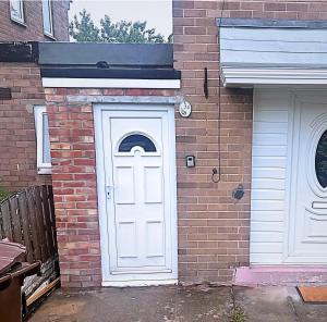 eine weiße Tür an der Seite eines Backsteingebäudes in der Unterkunft NEW Spacious 6 Guests House Sheffield WIFI Parking in Ecclesfield