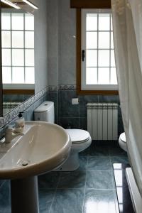 a bathroom with a sink and a toilet and windows at Apartamento turístico en la Ribeira Sacra in Sober +34 photos