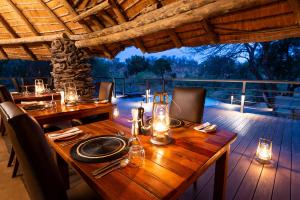 Una mesa de madera con platos y velas en una terraza. en Makalali River Lodge, en Hoedspruit