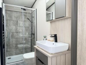 ein Badezimmer mit einem weißen Waschbecken und einer Dusche in der Unterkunft Stewarts Resort Lodge 41 in St Andrews + 8 Fotos