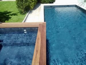 una piscina con agua azul y un borde de madera en Villa Zen, en Pinet