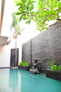 een standbeeld in het water naast een muur bij Villa Tentrem Legian in Legian