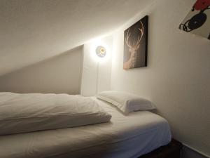 een slaapkamer met een wit bed met een hertenfoto aan de muur bij Maison Seguret 50mt from sky lifts in Sauze dʼOulx
