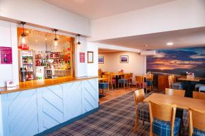 a restaurant with a bar and tables and chairs at Claxton Hotel in Redcar