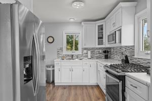 a kitchen with white cabinets and a stainless steel refrigerator at Charming Duplex on Main in St. Charles