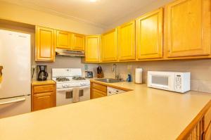 a kitchen with wooden cabinets and a white microwave at Kihei Akahi Resort - Unit D114 in Wailea