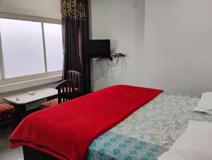 ein Schlafzimmer mit einer roten Decke auf einem Bett in der Unterkunft HOTEL GRAND GLORRYy in Pauri