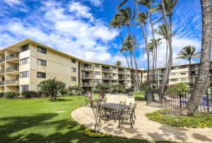 a resort with a table and chairs and palm trees at Kanai A Nalu 315 in Wailuku