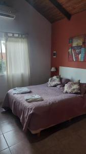 a bedroom with a bed with purple sheets and a window at La Nilda in Tandil