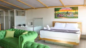 グアタペにあるHotel Stay Guatape a dos cuadras del parqueのベッドと緑のソファのある寝室 +64枚の写真