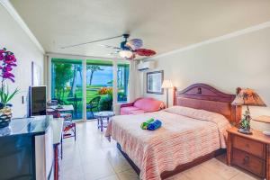 a bedroom with a bed and a living room with a television at Islander on the Beach 163 in Kapaa +46 photos