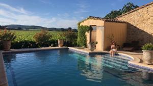 une femme assise dans une piscine dans une maison dans l'établissement La Rose des Vins, à Pouzolles