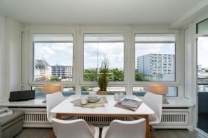 a dining room with a table and chairs and windows at Am Stadtpark in Westerland (Sylt)