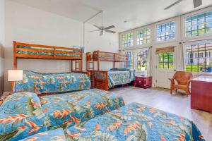 a bedroom with two beds and a desk and windows at Anahola Beach House 6br in Anahola