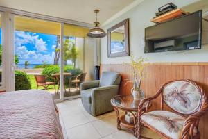 a bedroom with a bed and a tv and a chair at Islander on the Beach 152 in Kapaa