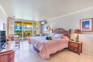 a bedroom with a bed and a television and a balcony at Islander on the Beach 305 in Kapaa +45 photos