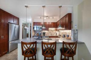 a kitchen with a large island with two bar stools at Ma'alaea Banyans 209 in Wailuku