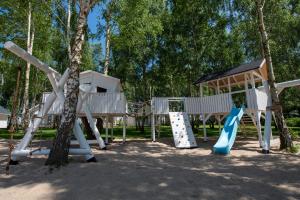 a playground with a slide and a tree at Off White Domki Darłówko in Darlowko