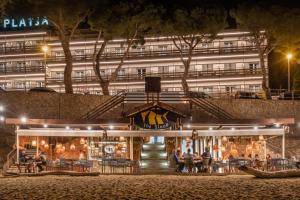 people sitting outside of a building at night at Canyelles Platja in Roses