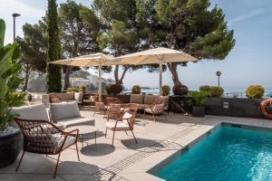a patio with chairs and umbrellas next to a swimming pool at Canyelles Platja in Roses