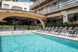 a swimming pool with chairs and a building at Canyelles Platja in Roses