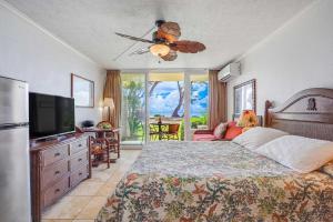 a bedroom with a bed with a ceiling fan and a television at Islander on the Beach 131 in Kapaa +47 photos