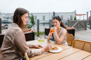 two women sitting at a table with a plate of food at Hotel de Timmerfabriek I Kloeg Collection in Vlissingen