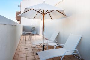 une terrasse avec des chaises blanches et un parasol dans l'établissement Hotel Castellon Center Affiliated by Meliá, Castellón de la Plana