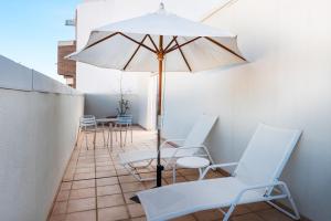 a patio with white chairs and an umbrella at Hotel Castellon Center Affiliated by Meliá in Castellón de la Plana