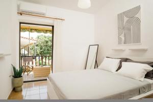 Un dormitorio blanco con una cama y un balcón. en Elle74 Platanidia, en Platanidia