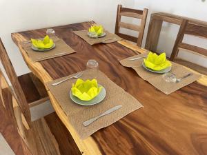 a wooden table with yellow napkins and plates on it at friar's bay paradise in Friar's Bay