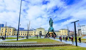 un grupo de personas caminando por un edificio con una estatua en Xena, en Belgrado