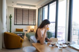 a woman sitting at a table in a living room at Evripidou 7 - Kalamata Mediterranean Suites in Kalamata