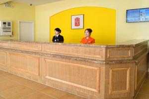 two people standing at a counter in a waiting room at Home Inn Shanghai Nicheng Lingang Facility Industrial Park in Nanhui