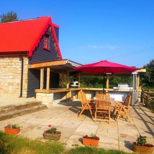 a patio with a table and chairs and an umbrella at Caitríona's Cottages - Adult Only Pet Friendly - Hot Tub, Sauna, Pool - Sleeps 4 in Rossinver