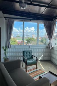 a living room with a green chair and a large window at ASAYA House in Chiang Mai