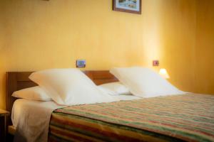 a bedroom with a bed with white sheets and pillows at Hotel Beau Sejour Pré-Saint-Didier in Pré-Saint-Didier