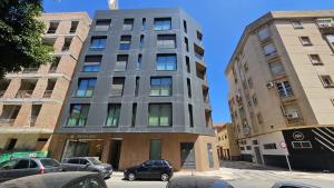 een hoog gebouw in een stadsstraat met geparkeerde auto's bij Elite Beach in Málaga