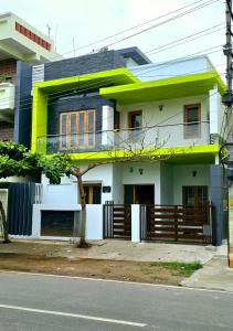 a white house with green trim on a street at Nandan home stay in Mysore