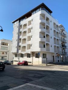 ein großes weißes Gebäude mit einem davor geparkten roten Auto. in der Unterkunft Hotel Aurora in Vieste
