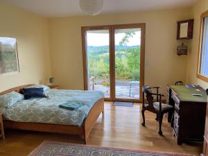 a bedroom with a bed and a desk and a window at Poulou Pyrénées in Gelos